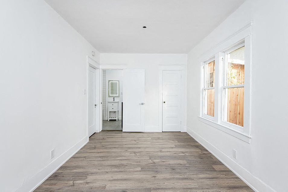 Bedroom with bathroom and large windows at 4141 Normal Avenue apartment homes in Los Angeles, California.
