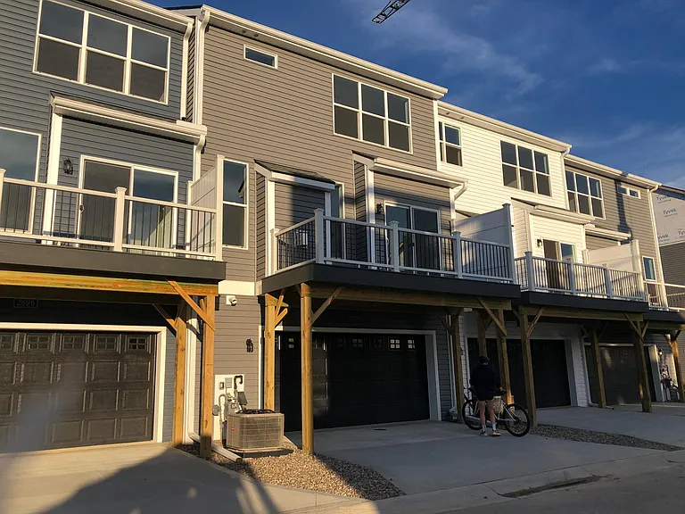Street view from back of townhouse that shows 2-car garage and balcony.