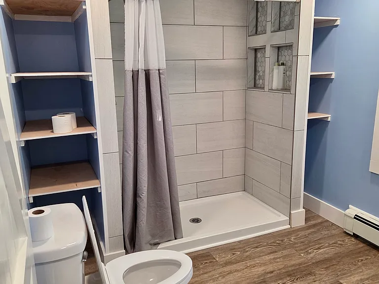 Fully-renovated bathroom with large walk-in shower and plenty of storage for towels and linens.