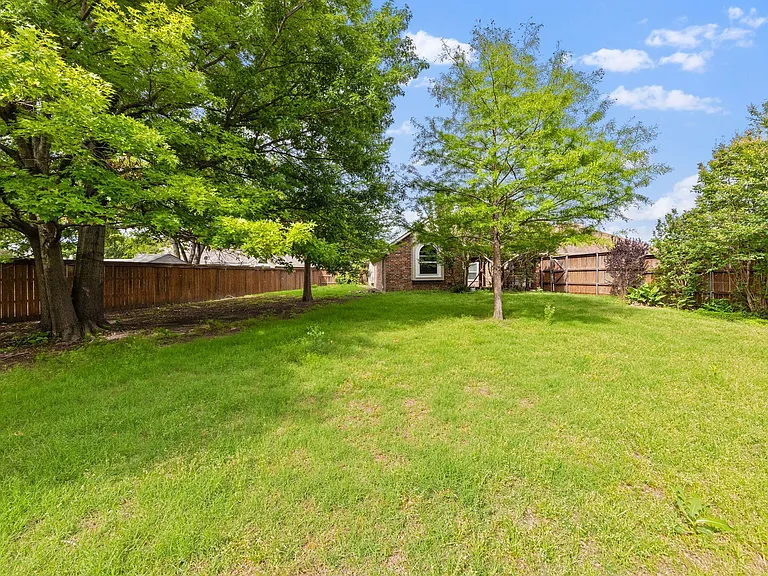 Spacious fenced backyard with mature shade trees and open lawnideal for relaxing outdoors or weekend gatherings.