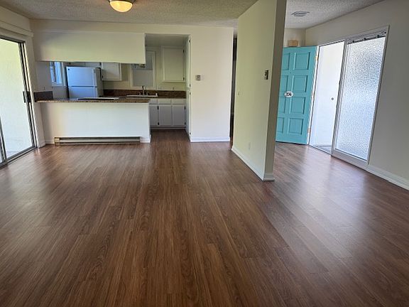 Very spacious living and dining room with kitchen in background-new cabinet paint and new refrigerator