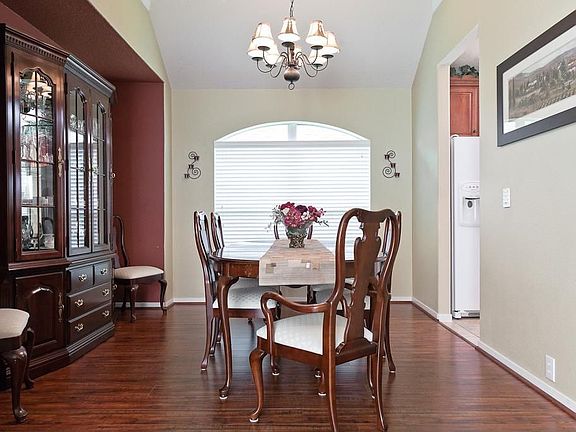 The dining room has laminate hardwood flooring, a chandelier, high ceiling and a furniture niche for a china cabinet or buffet.