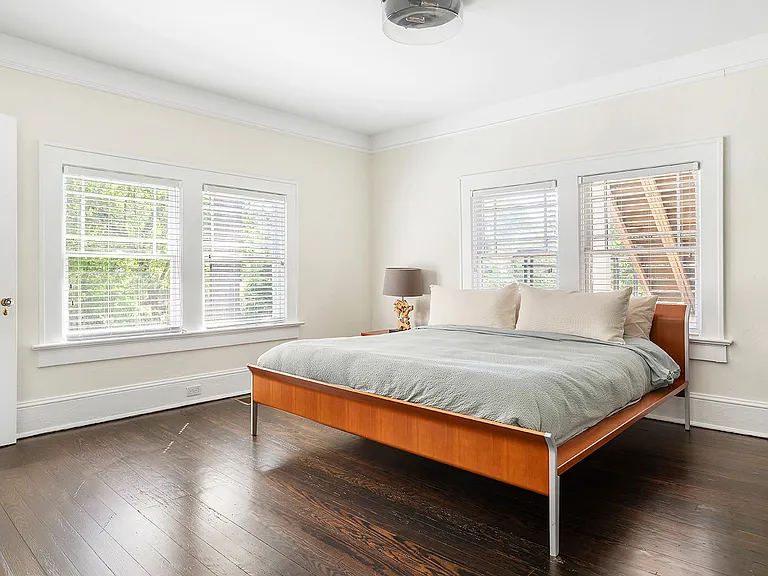 Large, quite bedroom with TV, linens from Parachute, and dresser drawers and closet