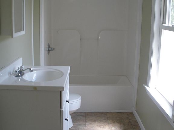 East-facing bathroom window (with frosted lower glass) provides lots of morning sunshine on the tiled floor and off-white walls.