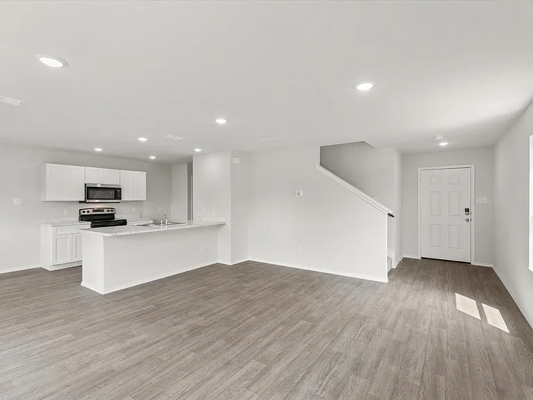 Open-concept living space recessed lighting, and a kitchen with white cabinetry, a bar-height counter, and stainless steel appliances