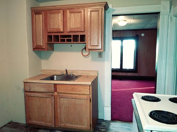 Decorative kitchen cabinets and sink as well as a view south into the largest living room. The kitchen floor is vinyl and very easy to keep clean. The bath is accessed from the east kitchen wall.