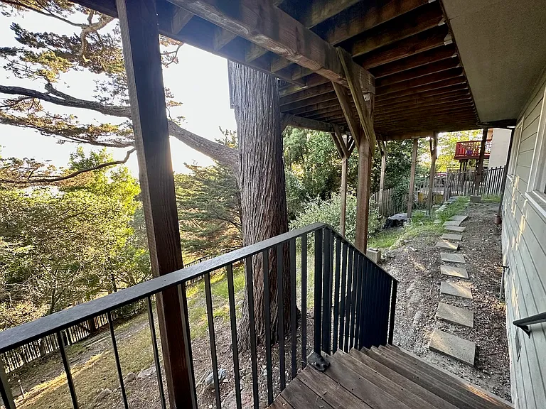 Stairs from lower deck that lead to side of house with dog run.