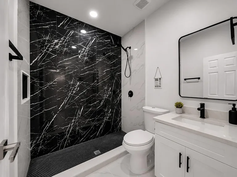 Stylish bathroom with a walk-in shower, bold tile surround, and a sleek vanity with ample counter space and storage.