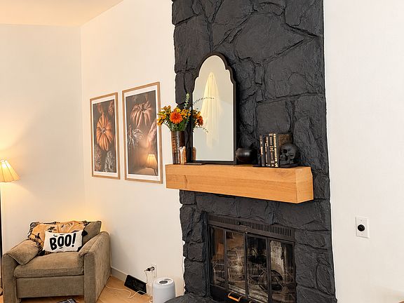 Floor-to-ceiling stone wood burning fireplace with a white oak mantel.