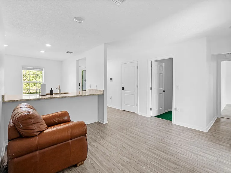 Open-concept living area with durable plank flooring, recessed lighting, and a breakfast bar overlooking the kitchen.
