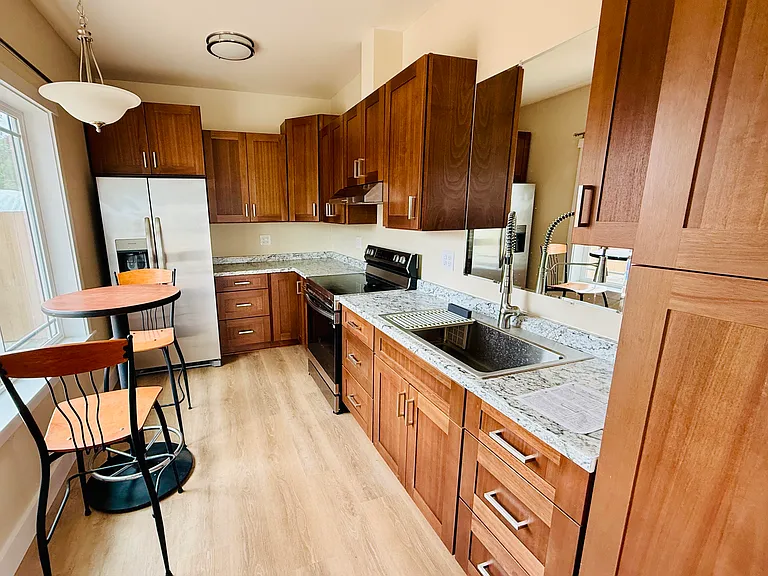 Full-size kitchen with all new appliances: refrigerator and range/oven. Solid wood custom-built walnut cabinetry