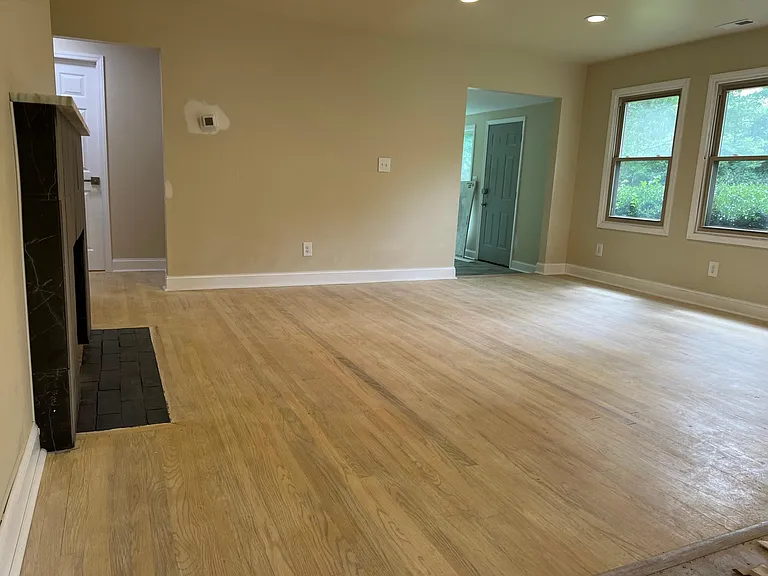 Bright and open living area with modern finishes, fresh paint, new floors, and cozy fireplace charm.