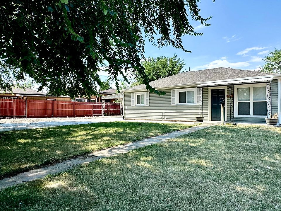 Charming single-story home with a well-maintained front lawn, vibrant red fence, and welcoming tree-lined path.
