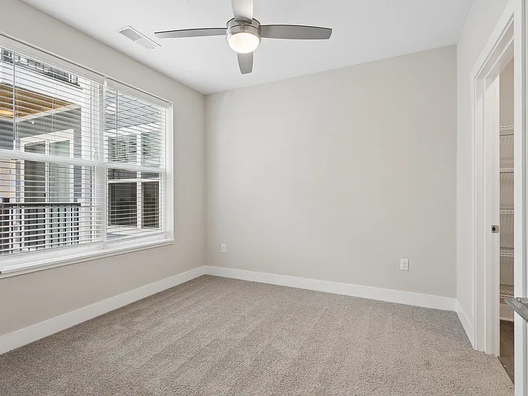Carpeted bedroom with ceiling fan of a Tiffany Flats apartment home.