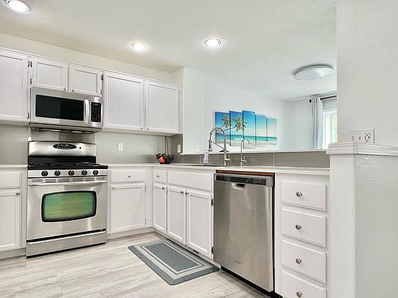 Modern kitchen with stainless steel appliances, quartz countertop, and large farmhouse sink.
