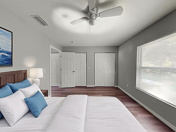 Bright and spacious bedroom featuring modern decor, large windows for natural light, and elegant ceiling fan.