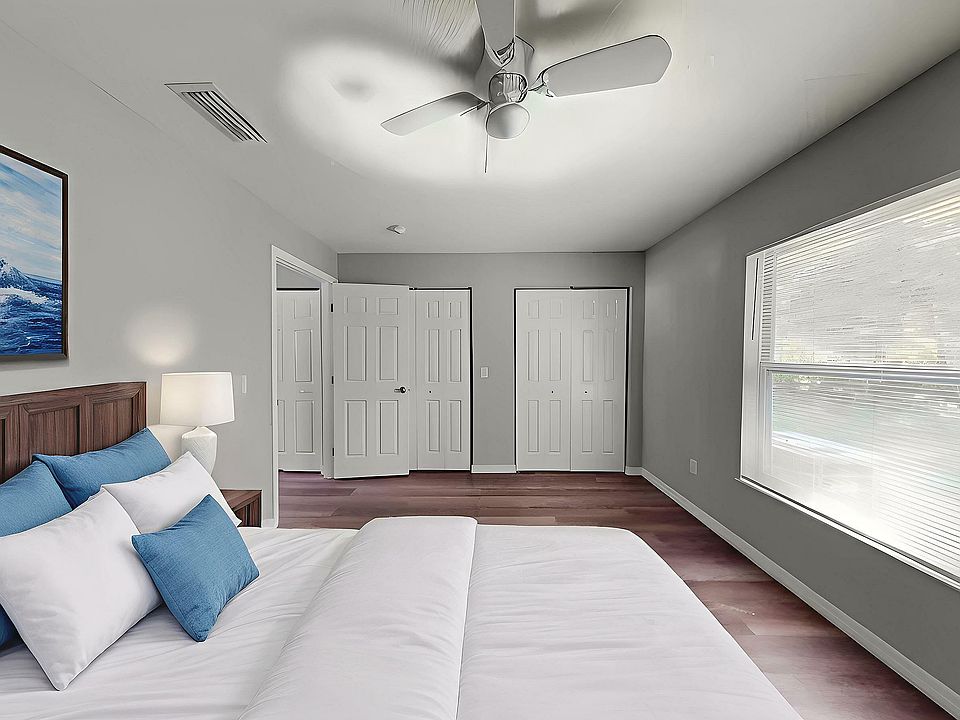Bright and spacious bedroom featuring modern decor, large windows for natural light, and elegant ceiling fan.