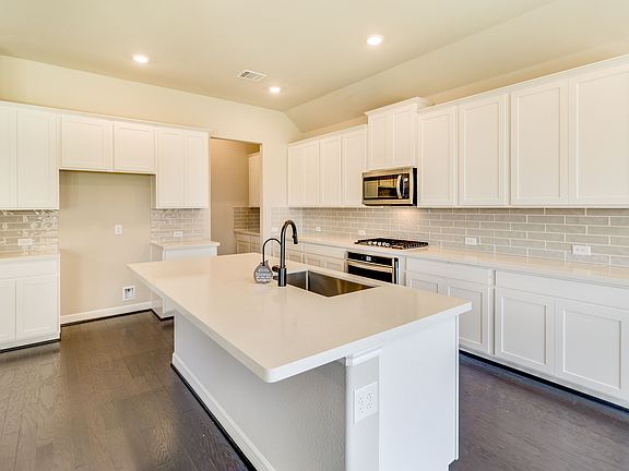 White kitchen with plenty of counterspace and kitchen island with overhang for additional seating