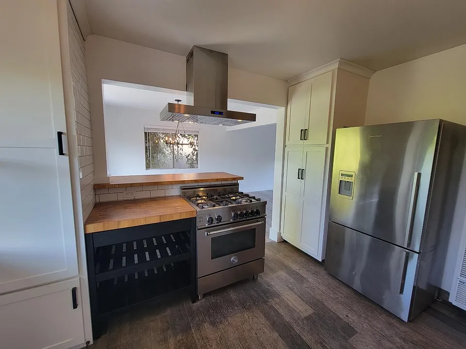 Stainless stove, exhaust fan, refrigerator and dishwasher. Decorator Butcher block counter with storage for pans and trays below.