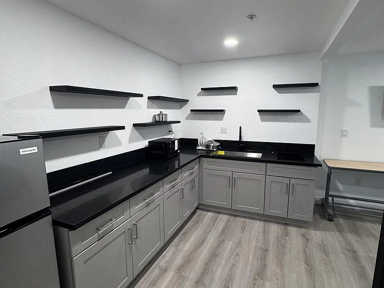 Spacious shared kitchen with ample cabinetry, open shelving, and long counters plus a sink and compact appliances.