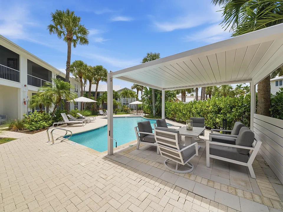 Oasis like pool with beach chairs for tanning and shaded pergola for lounging