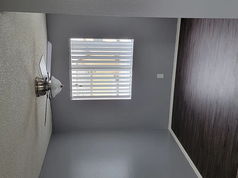Dining room with hardwood floor, large window, and ceiling fan at Grand Oaks Apartments in Lake Elsinore, California.