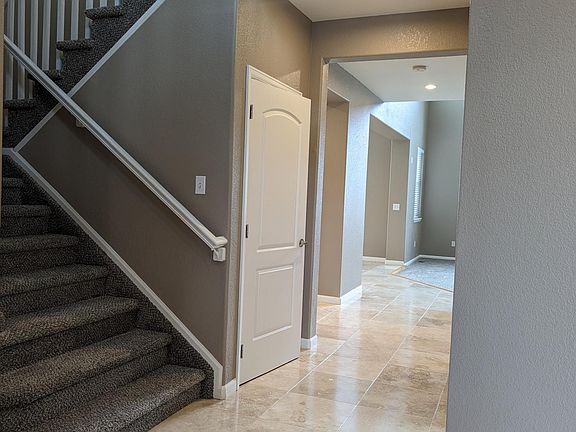 View down the hall as you enter the house through the front door. The kitchen is on the left and the great room is on the right. The beautiful stone floor is travertine.