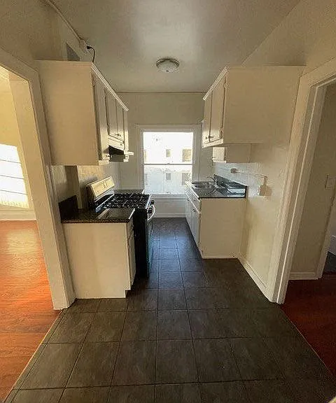 Kitchen with white cabinets and gas range in apartment unit of Molinio Del Mar Apartments in Pasadena, California.