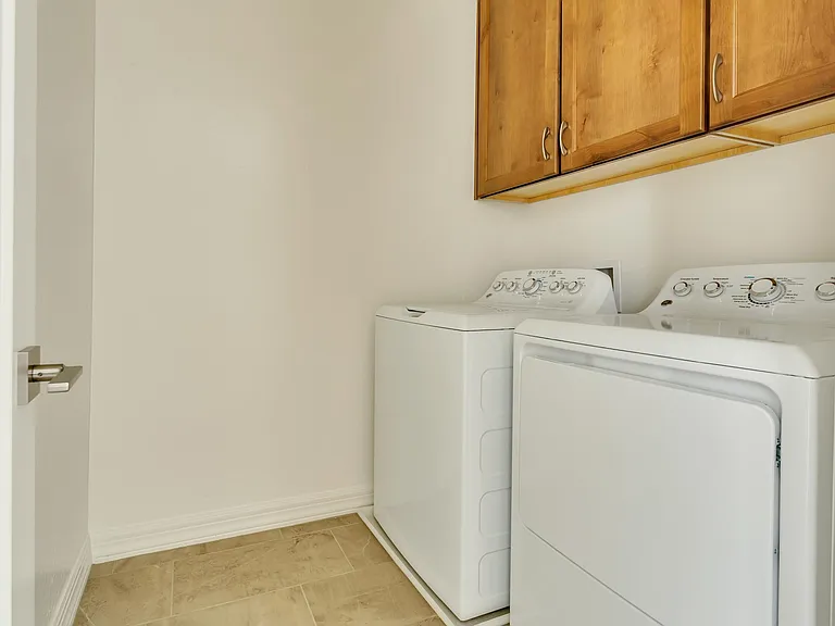 Full size washer/dryer in the laundry room with additional cabinetry above.