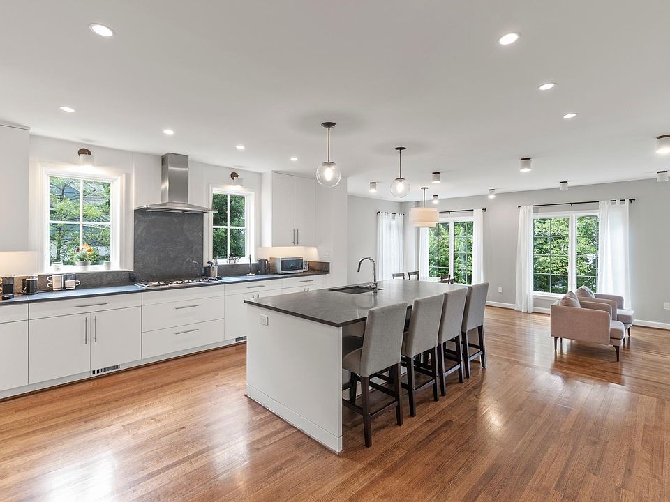 Modern kitchen with stainless steel appliances, transitioning to a living space surrounded by natural light