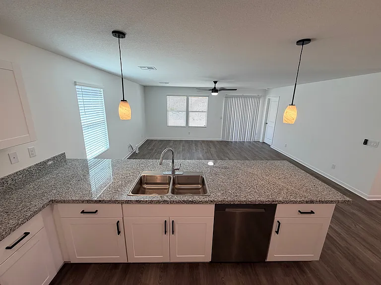 Open space from kitchen to living room with bar seating at the kitchen counter