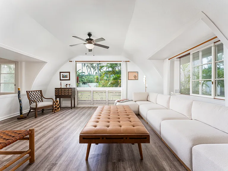 Spacious main living area featuring vaulted ceilings, abundant natural light, and tropical garden views.