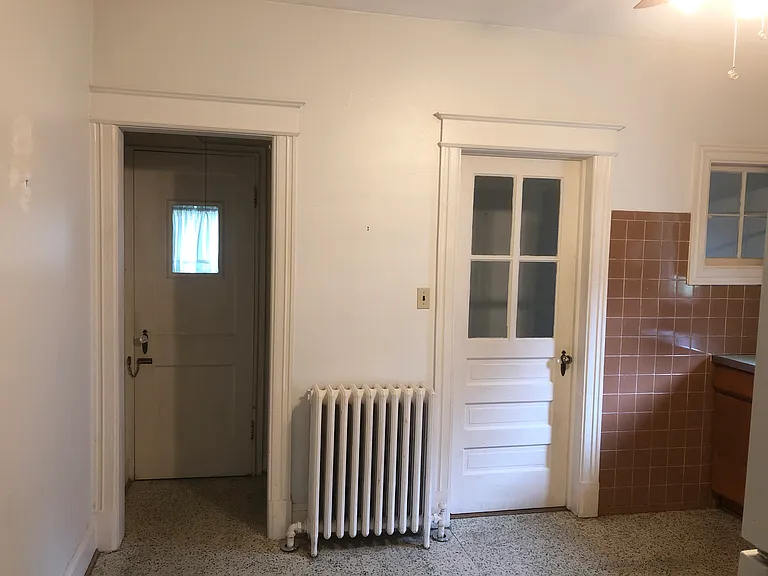 Kitchen area with door on left going past a pantry area leading to the Lower Level. Door on right goes to Upper Level and door to backyard