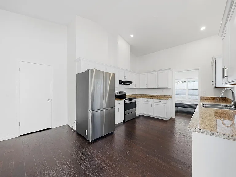 Spacious kitchen with granite counters, ample white cabinetry, stainless-steel appliances, and a double-basin sink.