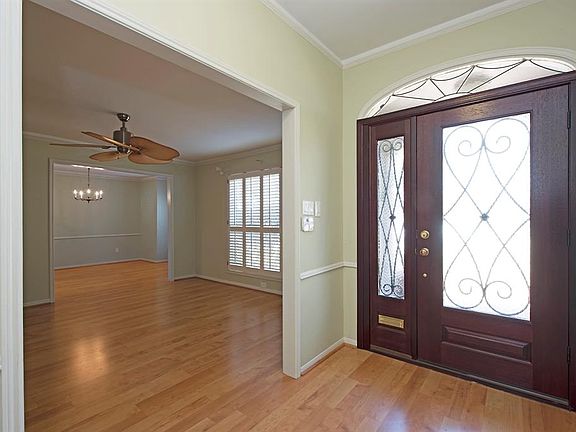 Foyer has gorgeous front door and wood flooring extending into formal living and dining.