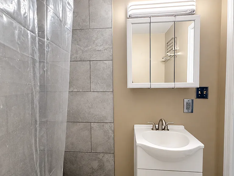 The bathroom features a charming clawfoot-style soaking tub with shower setup, white vanity, mirrored medicine cabinet, updated lighting, and neutral wall colors.