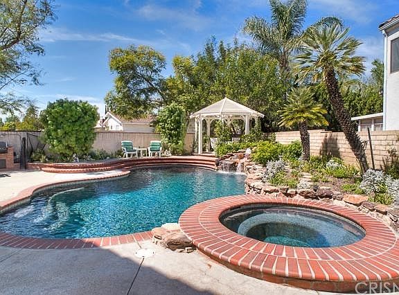 The beautiful entertainers backyard with sparkling pool & spa, mature landscaping, brick hardscaping, gazebo, and BBQ area.
