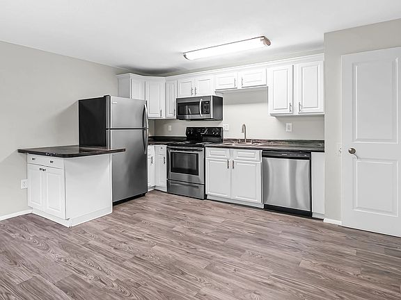 Experience harmonious living with an open-concept kitchen and living room both graced by stunning grey wood-style flooring.