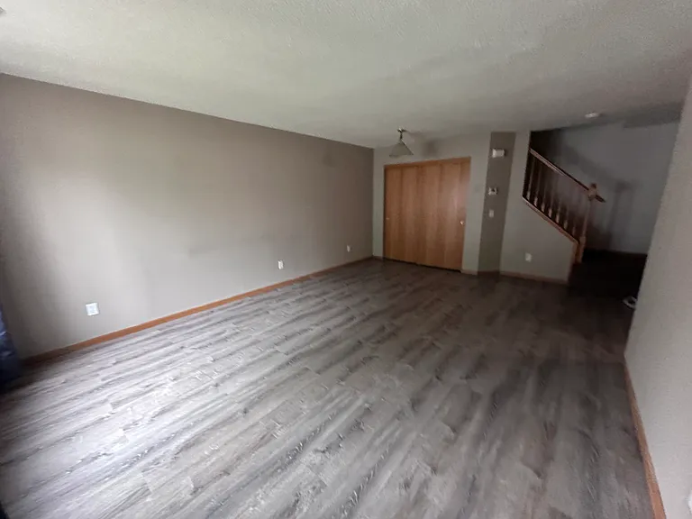 Open living space with new wide-plank flooring and stairs to the bedrooms
