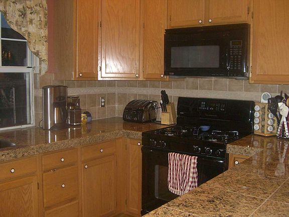 Gas stove and granite tile countertops, lots of kitchen storage