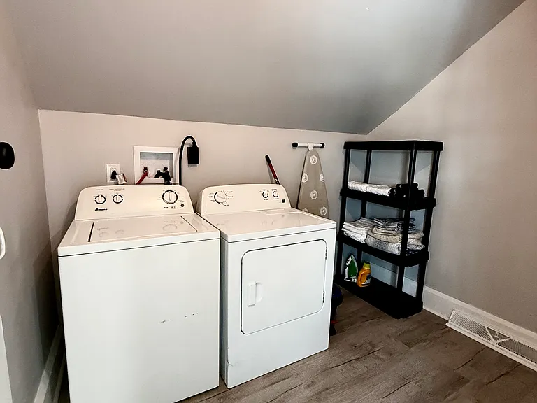 The spacious private laundry room features a washer and dryer, ample storage options, and an ironing board with an iron, providing everything you need for a convenient laundry experience.