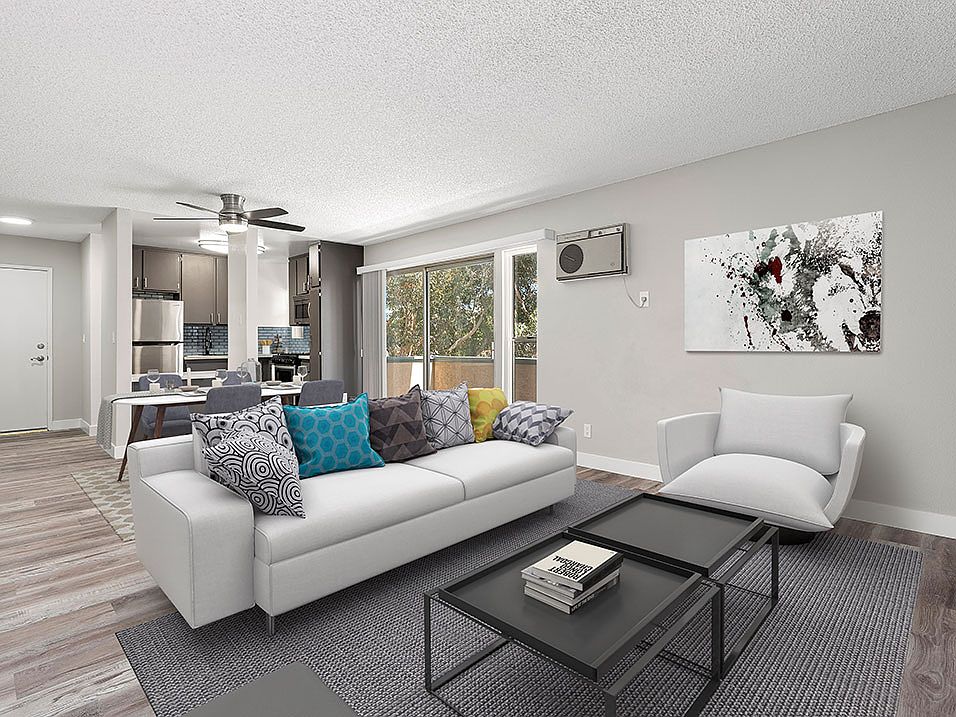 Hardwood floored living room with view of dining area, kitchen, and balcony.