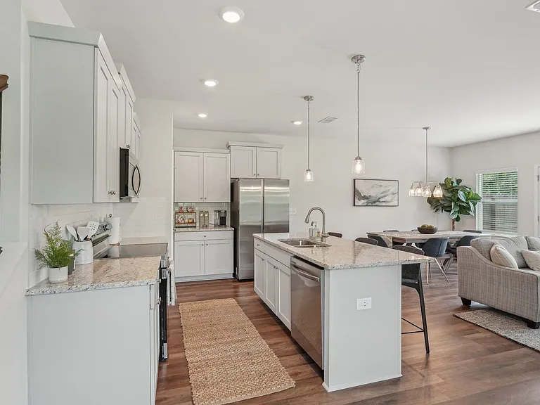 A modern kitchen showcasing a granite countertop island with bar seating and premium stainless steel appliances.