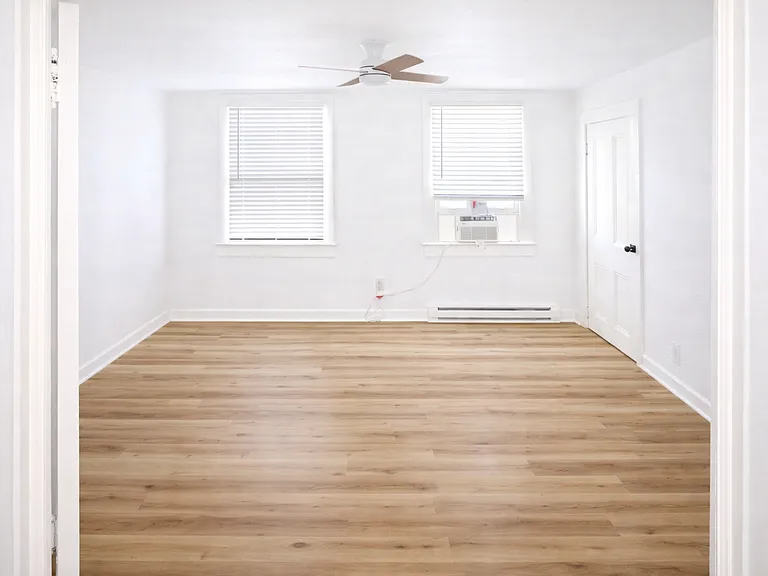 Bedroom with wood-style flooring, modern ceiling fan, new AC unit, baseboard heating, and a spacious closet