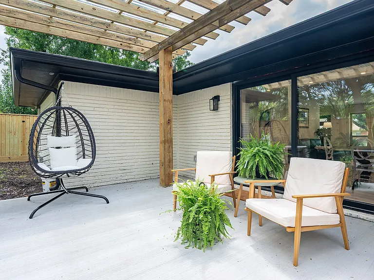 Private outdoor seating area with a modern pergola and direct access to the main living space, featuring a charming patio corner perfect for morning coffee or quiet afternoon relaxation.