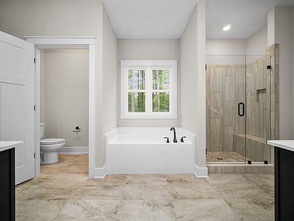 A modern bathroom with a bathtub, shower with glass door, toilet, and double sink vanity. The room h