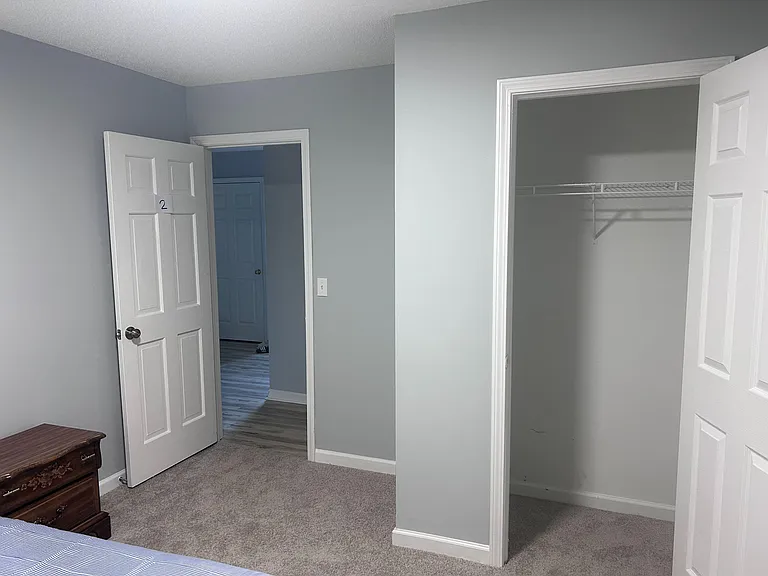 Spacious bedroom with a wide closet and neutral finishes, offering easy access to the hallway and nearby rooms.