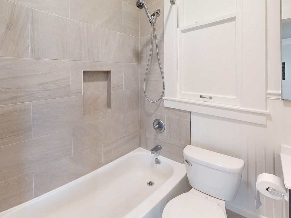 Bathroom with bathtub, showerhead, toilet, sink, faucet, and mirror in a clean setting