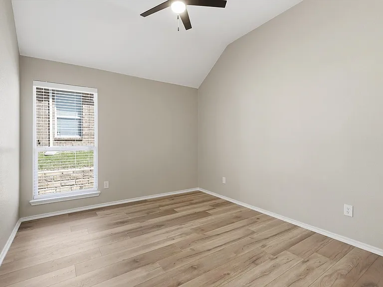 Room featuring vaulted ceilings, wood-finish flooring, a ceiling fan, and window with blinds