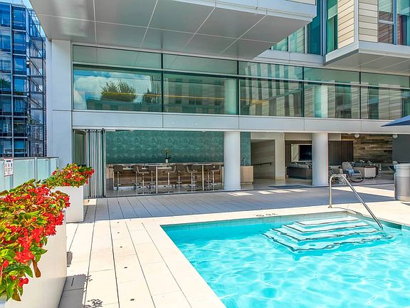 Upscale apartment amenities featuring a stylish pool deck, shaded bar seating, and a modern indoor-outdoor lounge space perfect for relaxing or entertaining.